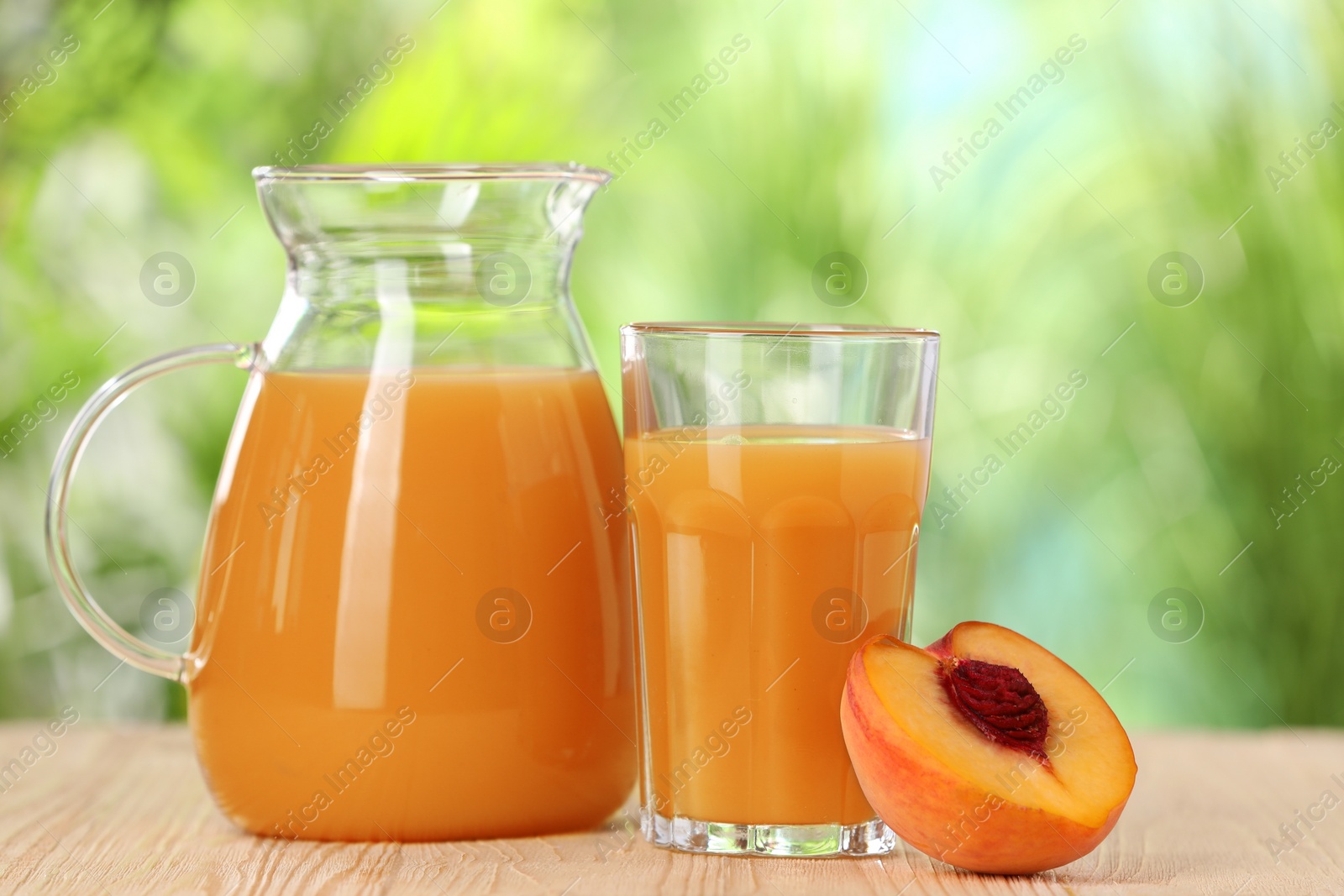 Photo of Tasty peach juice and fresh fruit on wooden table outdoors