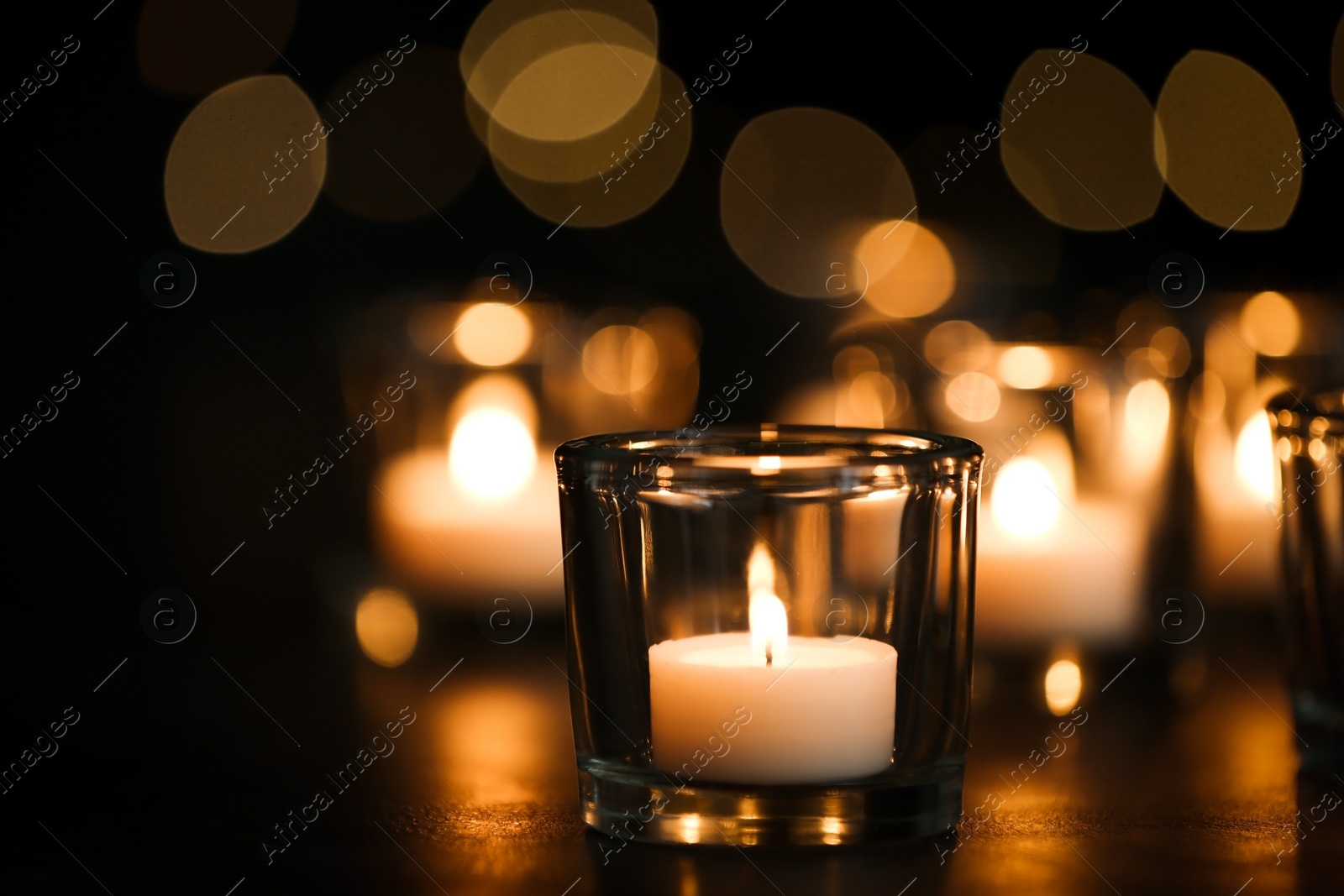 Photo of Burning candle on table against blurred background. Funeral symbol