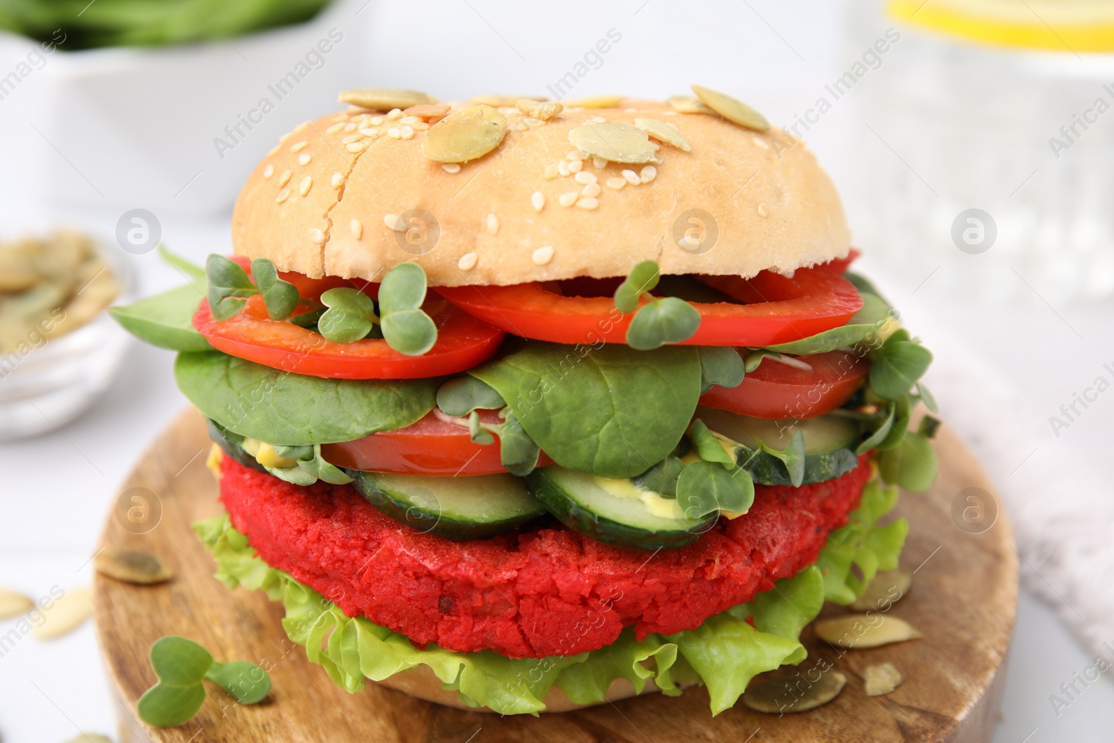 Photo of Tasty vegan burger with vegetables, patty and microgreens on white table, closeup