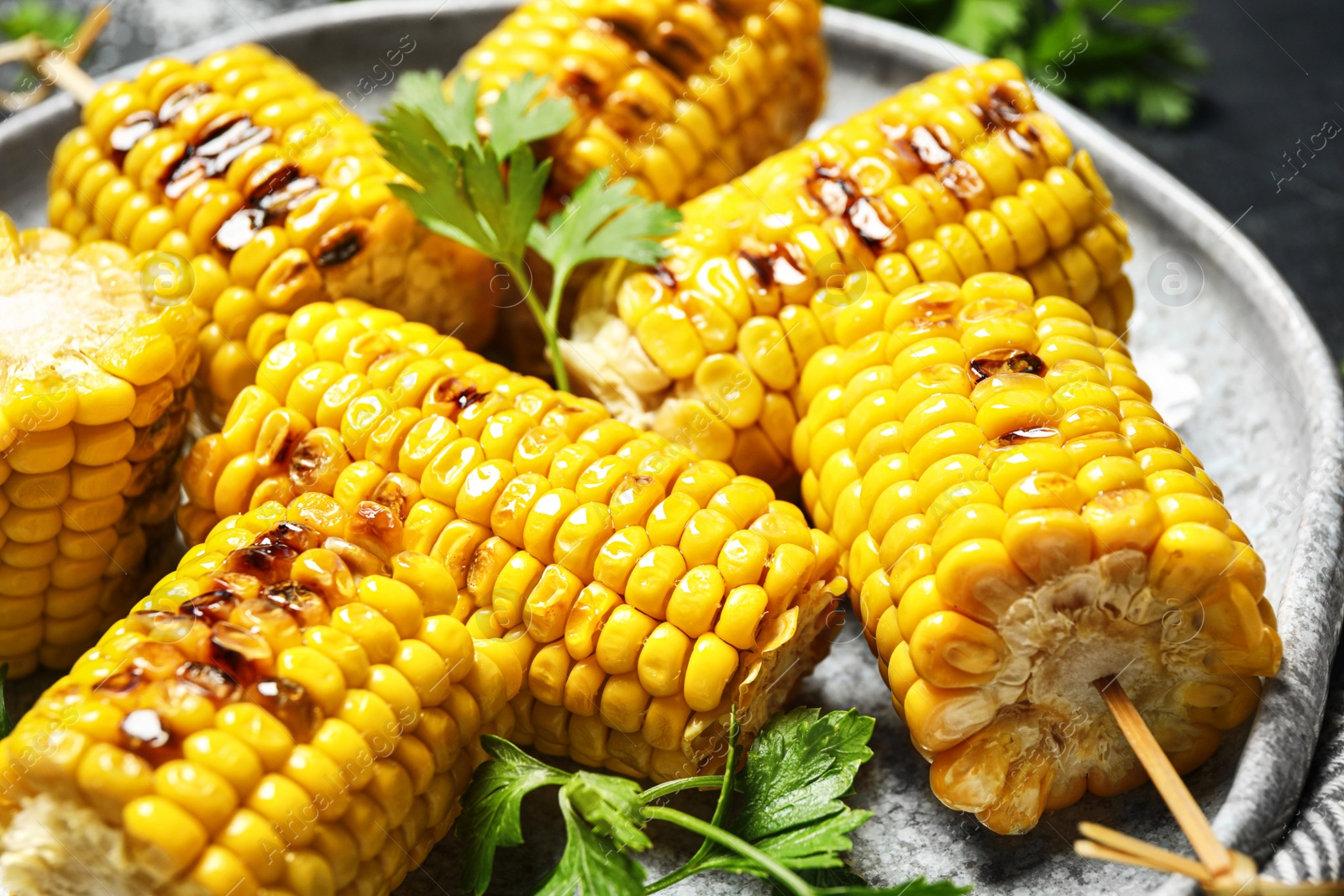 Photo of Delicious grilled corn cobs on plate, closeup