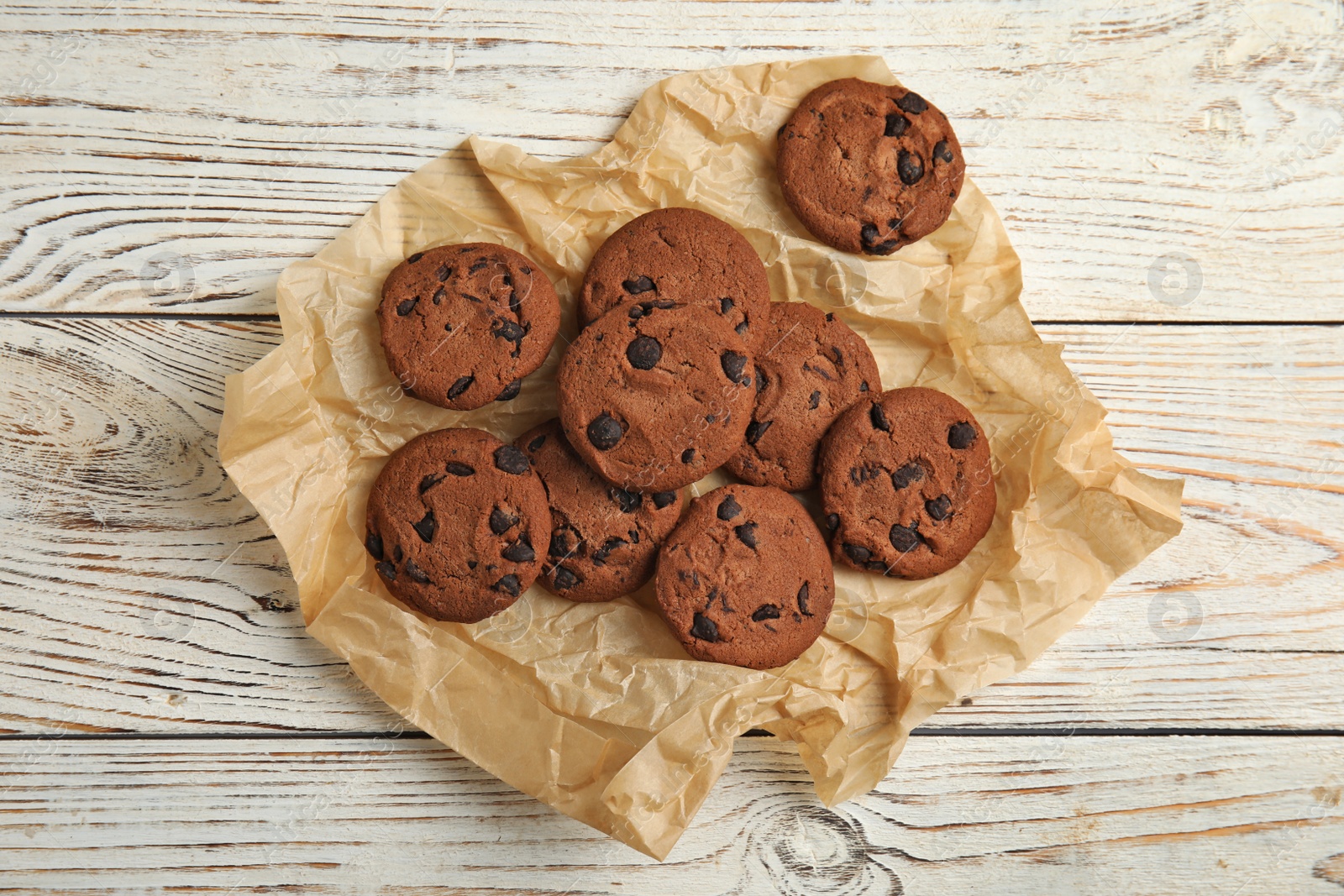 Photo of Delicious chocolate chip cookies on wooden table, flat lay