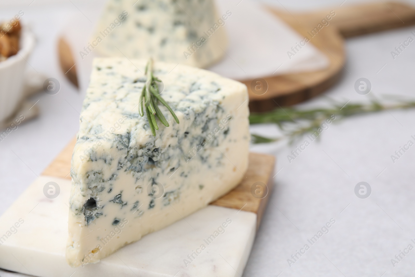 Photo of Tasty blue cheese with rosemary on light table, closeup. Space for text