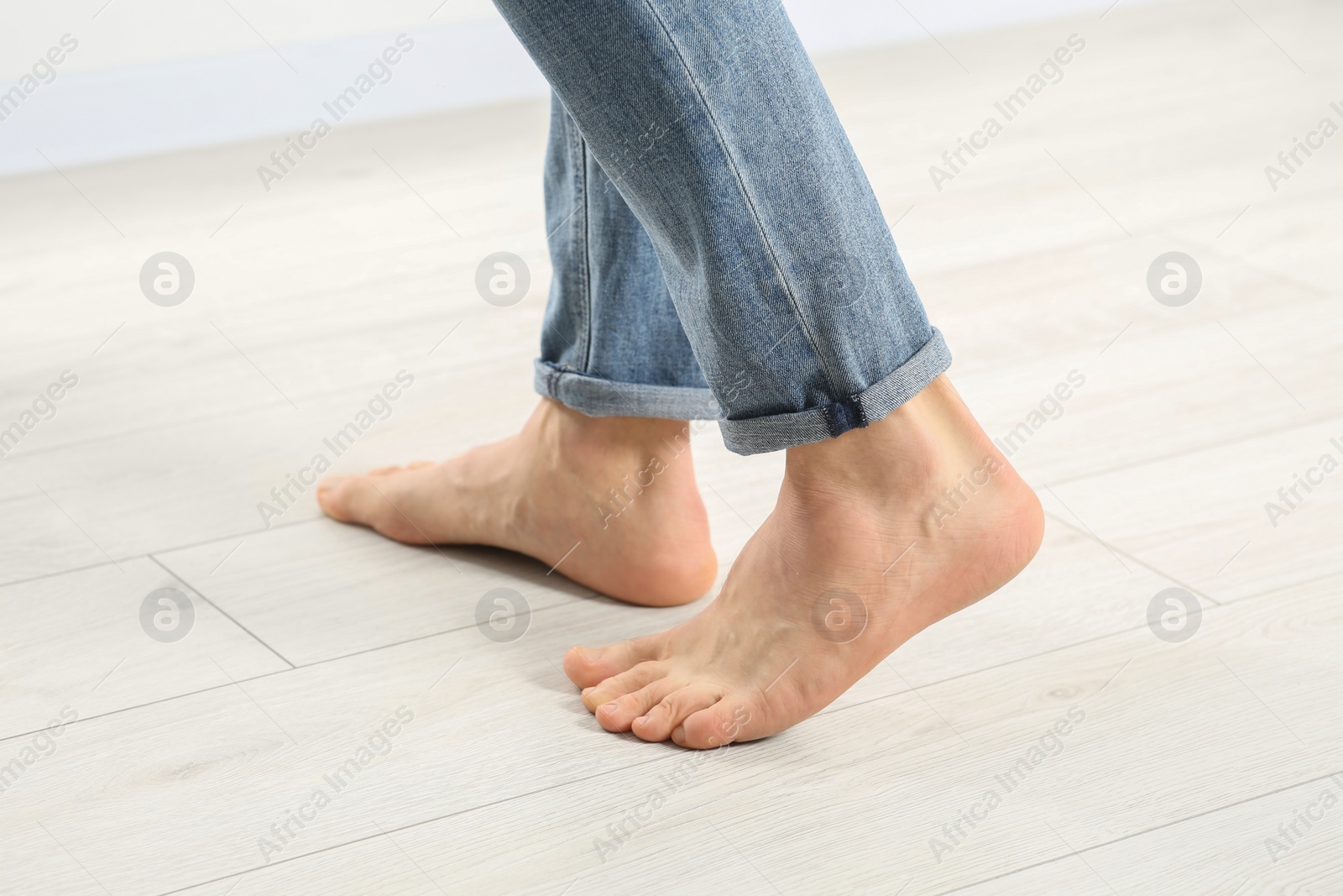 Photo of Barefoot woman walking on white parquet, closeup. Heated floor