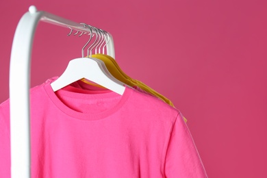 Rack with stylish children clothes on pink background, closeup. Space for text