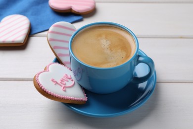 Photo of Delicious heart shaped cookies and cup of coffee on white wooden table, closeup