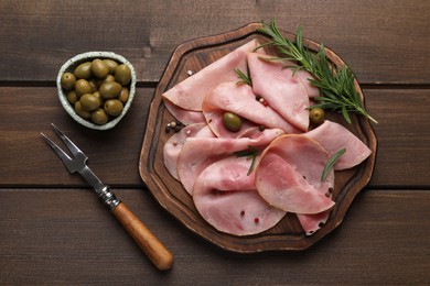 Slices of delicious ham with rosemary and olives served on wooden table, flat lay