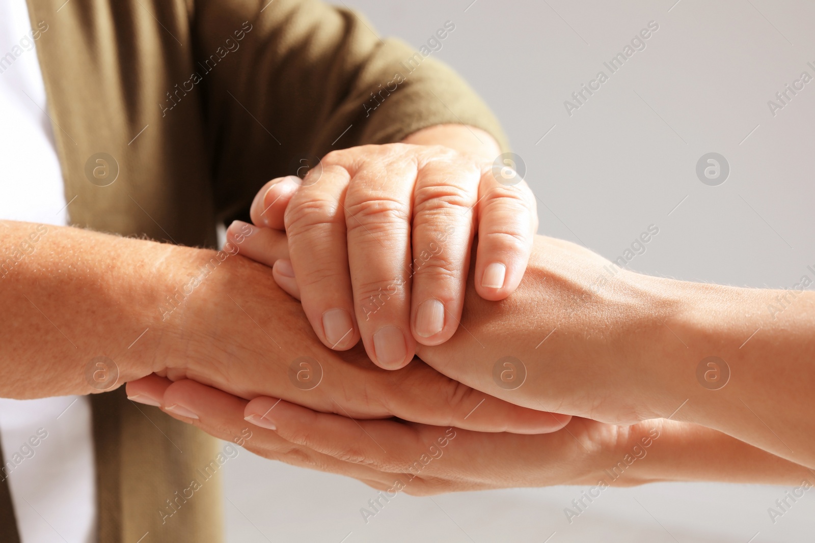 Photo of Helping hands on grey background, closeup. Elderly care concept