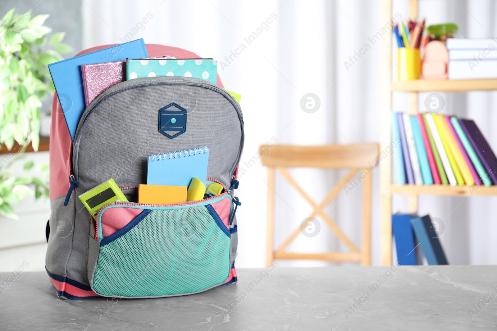 Photo of Stylish backpack with different school stationery on table indoors. Space for text