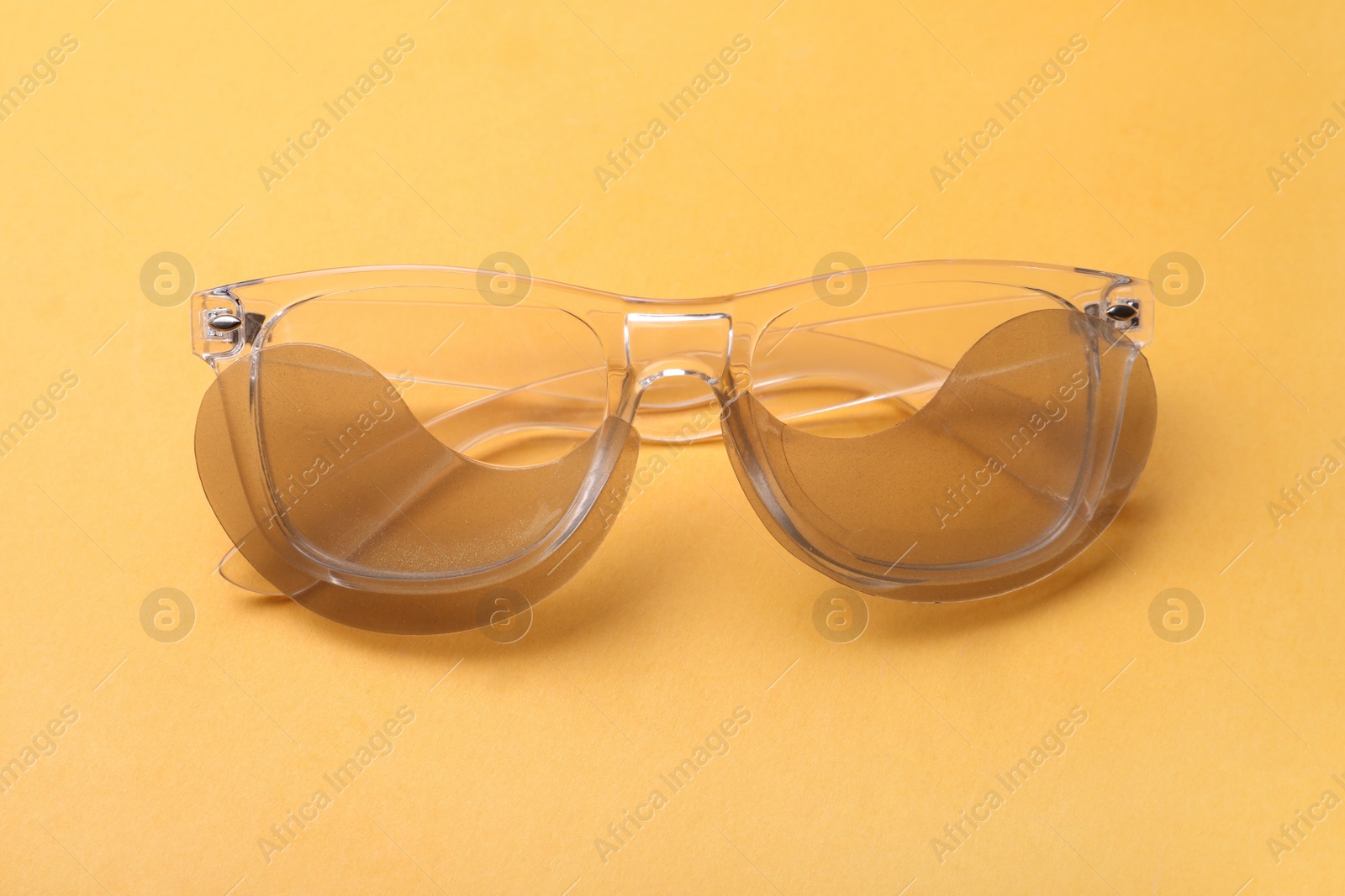 Photo of Glasses with under eye patches on orange background, closeup. Cosmetic product