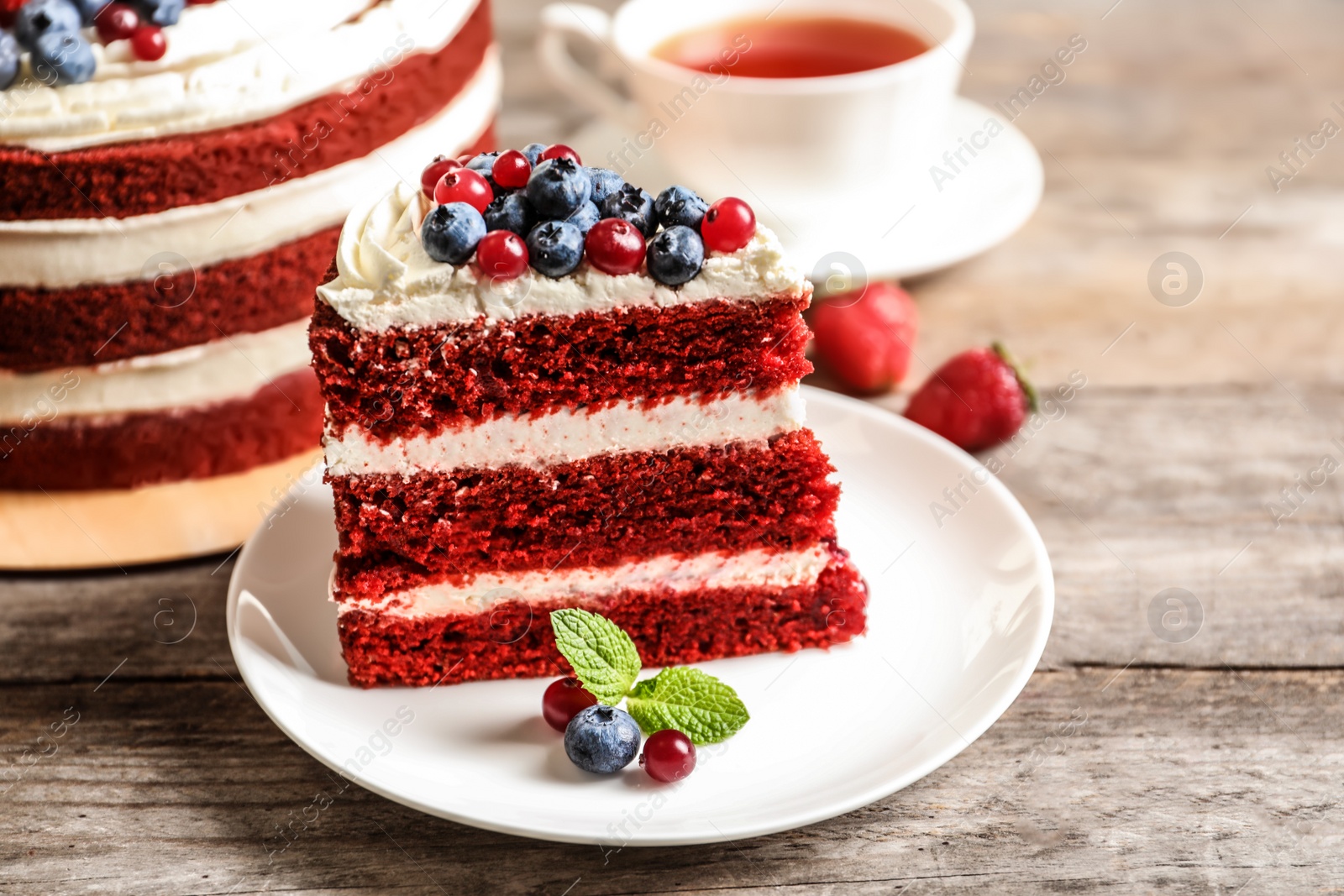 Photo of Plate with piece of delicious homemade red velvet cake on wooden table