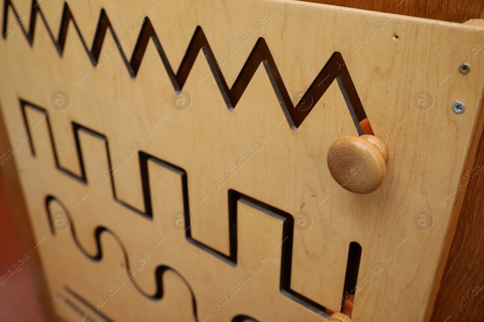 Photo of Wooden sliding maze with different lines on wall, closeup. Montessori toy