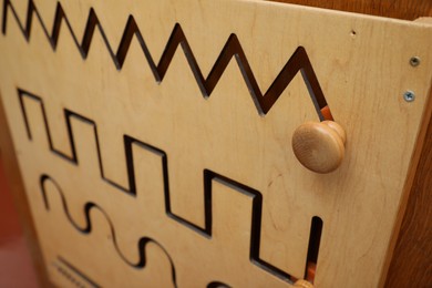 Photo of Wooden sliding maze with different lines on wall, closeup. Montessori toy