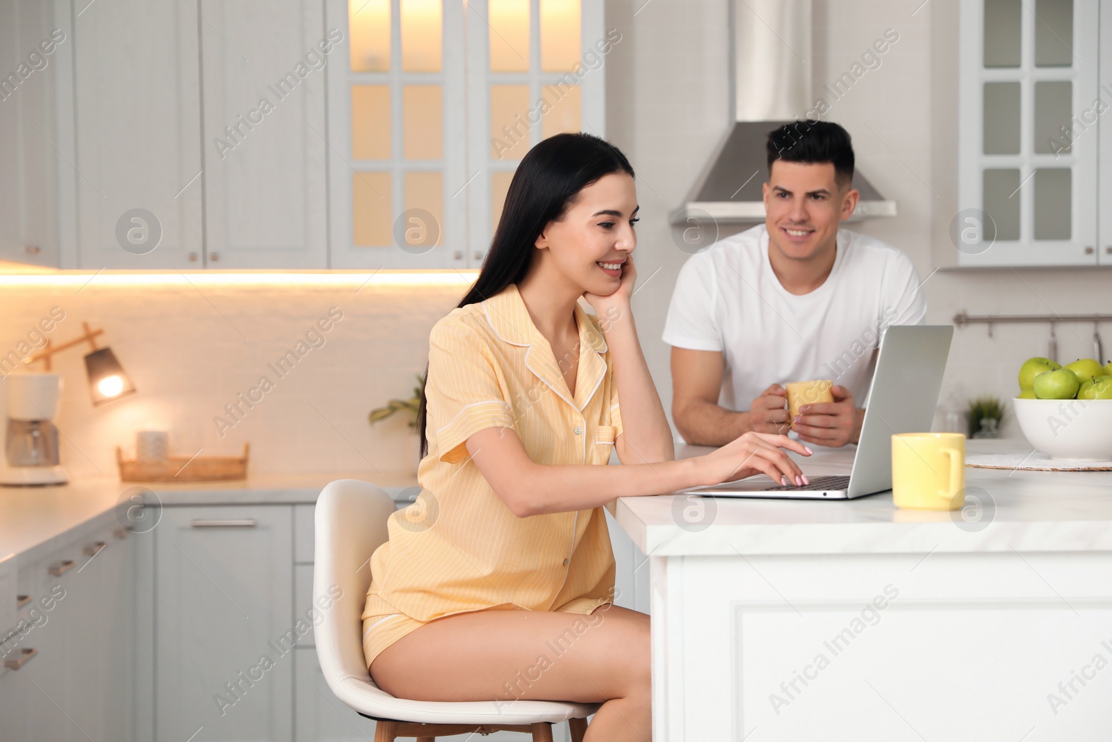 Photo of Happy couple wearing pyjamas and spending time together in kitchen