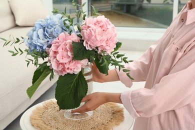 Woman with bouquet of beautiful hortensia flowers in living room, closeup