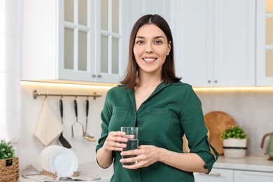 Photo of Young woman holding glass with clean water in kitchen