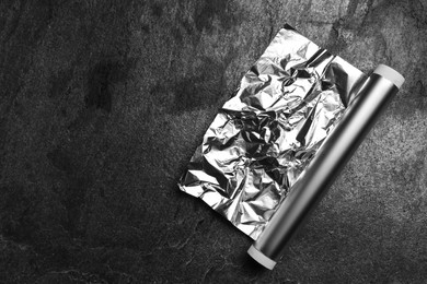 Photo of Roll of aluminum foil on grey table, top view. Space for text