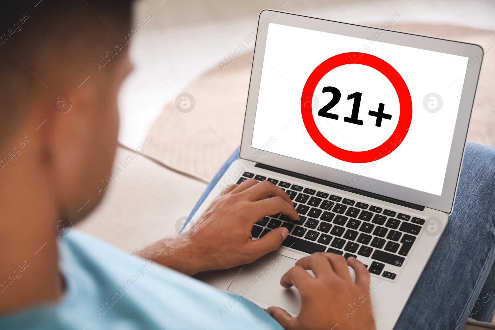 Image of Man using laptop with age limit sign 21+ years indoors, closeup