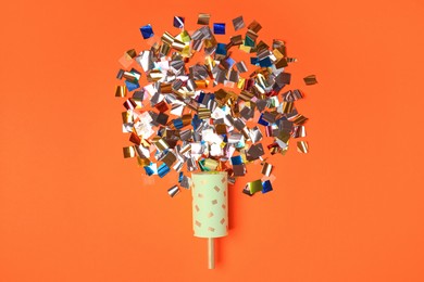 Photo of Party popper and colorful confetti on orange background, flat lay