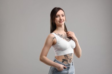 Photo of Portrait of beautiful tattooed woman on grey background
