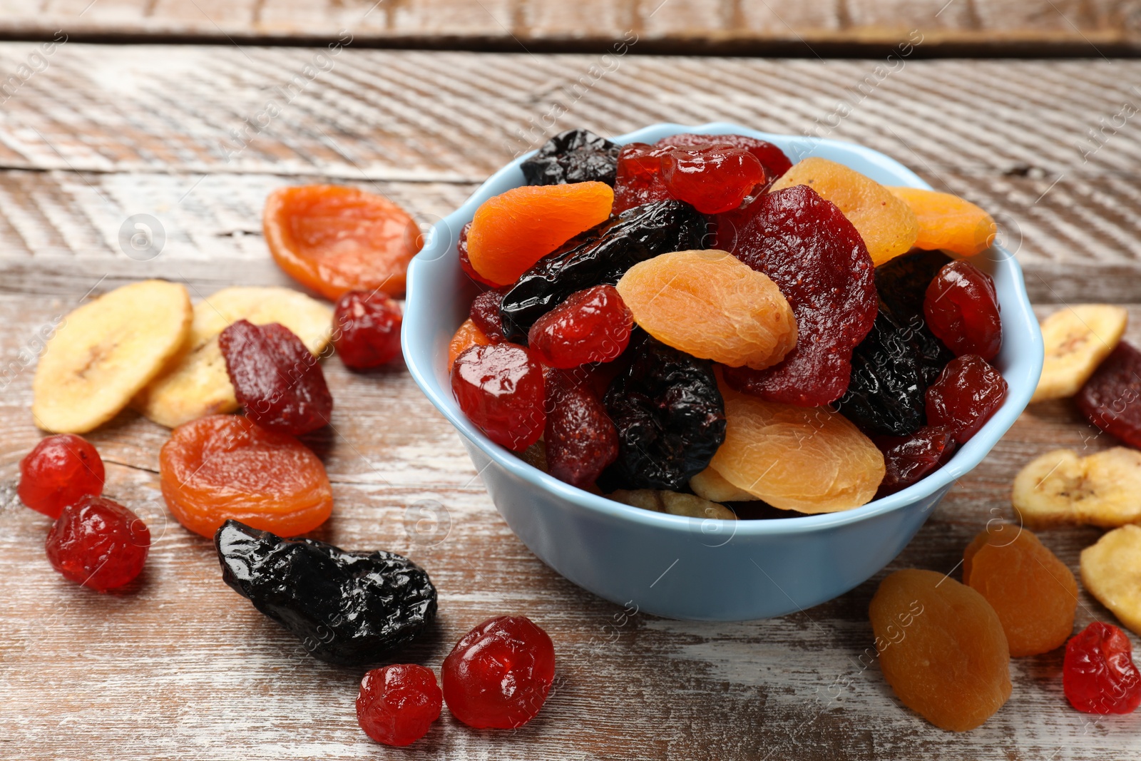 Photo of Mix of delicious dried fruits on wooden table, closeup