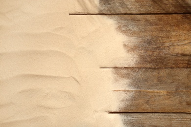 Beach sand on wooden background, top view with space for text