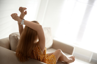 Photo of Young woman relaxing on couch near window at home. Space for text