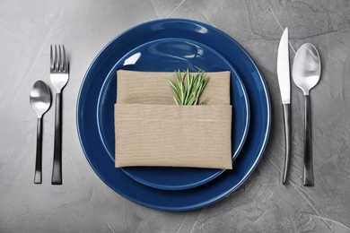 Photo of Beautiful table setting with cutlery, napkin and plates on grey background, top view