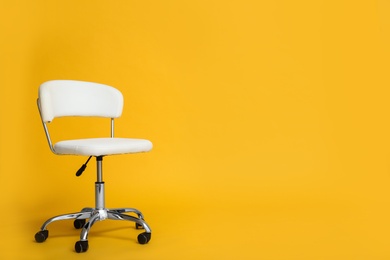 Modern office chair on yellow background. Space for text