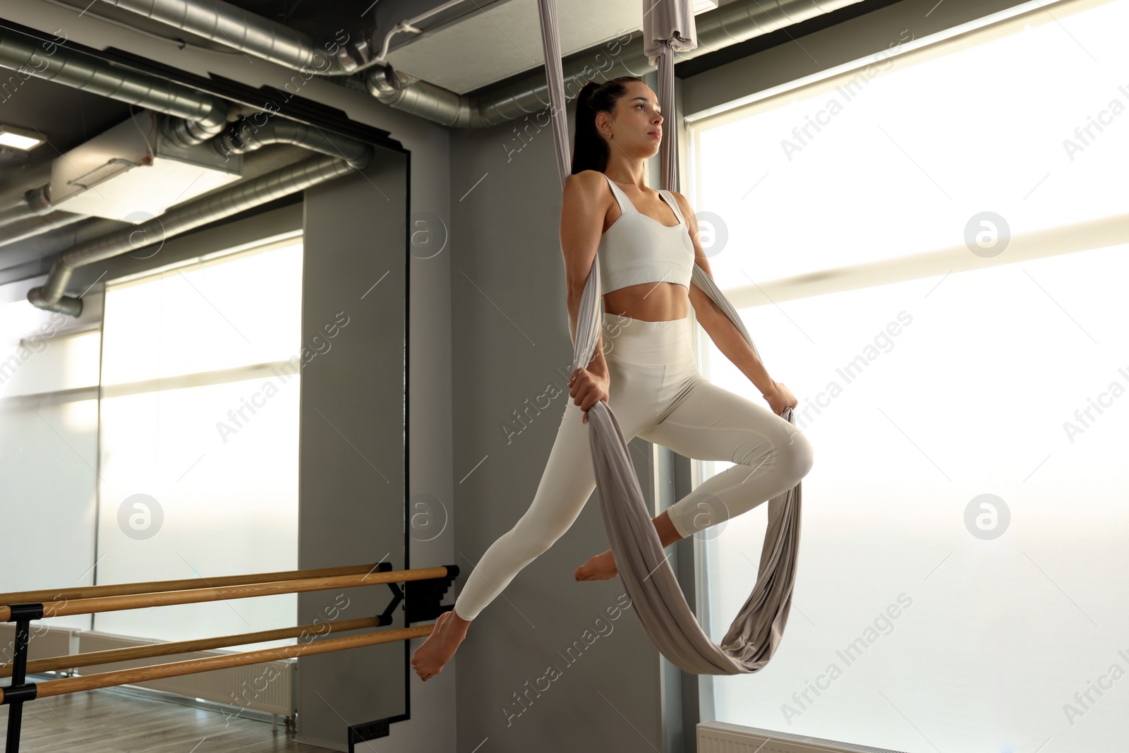 Photo of Young woman practicing fly yoga on hammock in studio