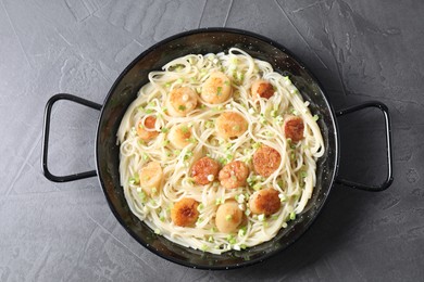 Photo of Delicious scallop pasta with green onion on grey table, top view