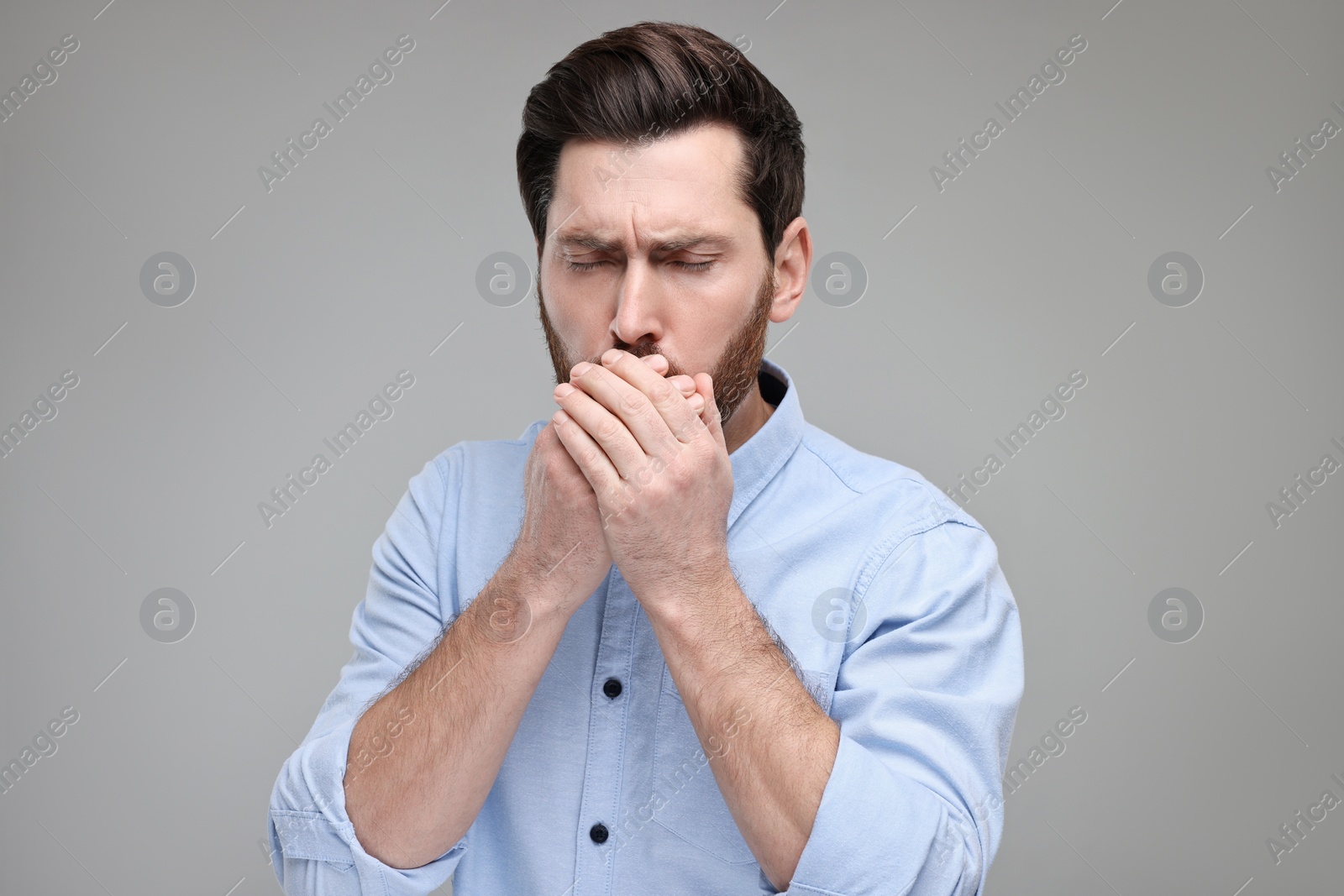 Photo of Sick man coughing on light grey background. Cold symptoms