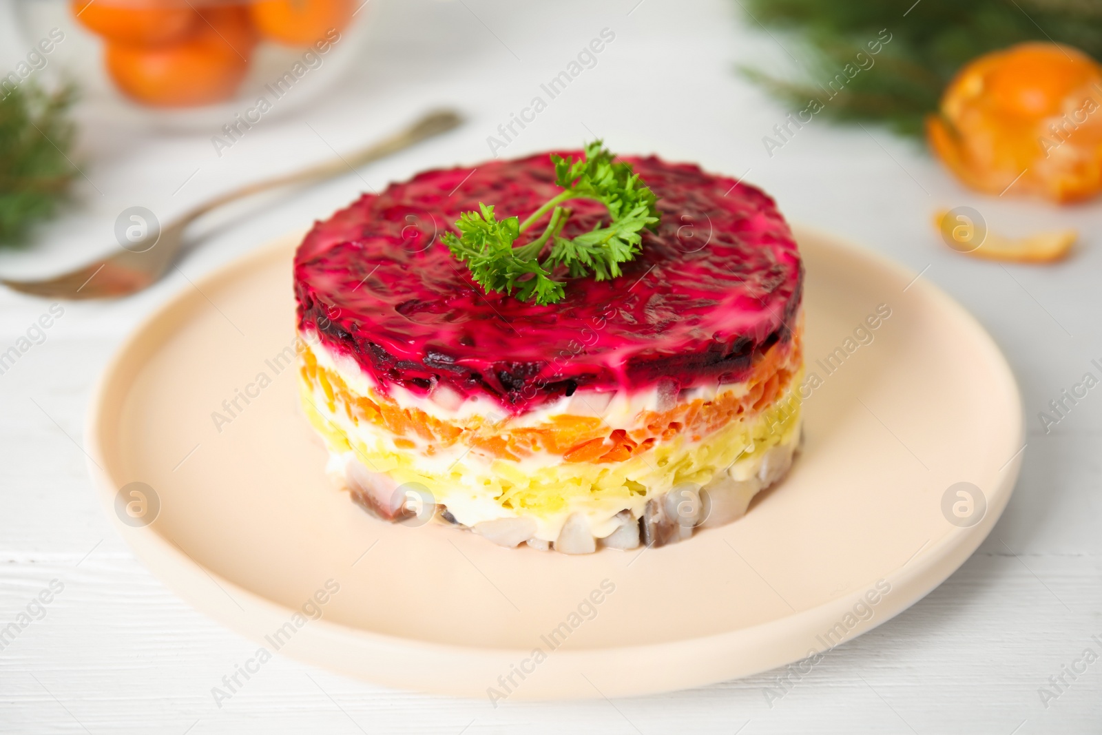 Photo of Herring under fur coat served on white wooden table. Traditional russian salad