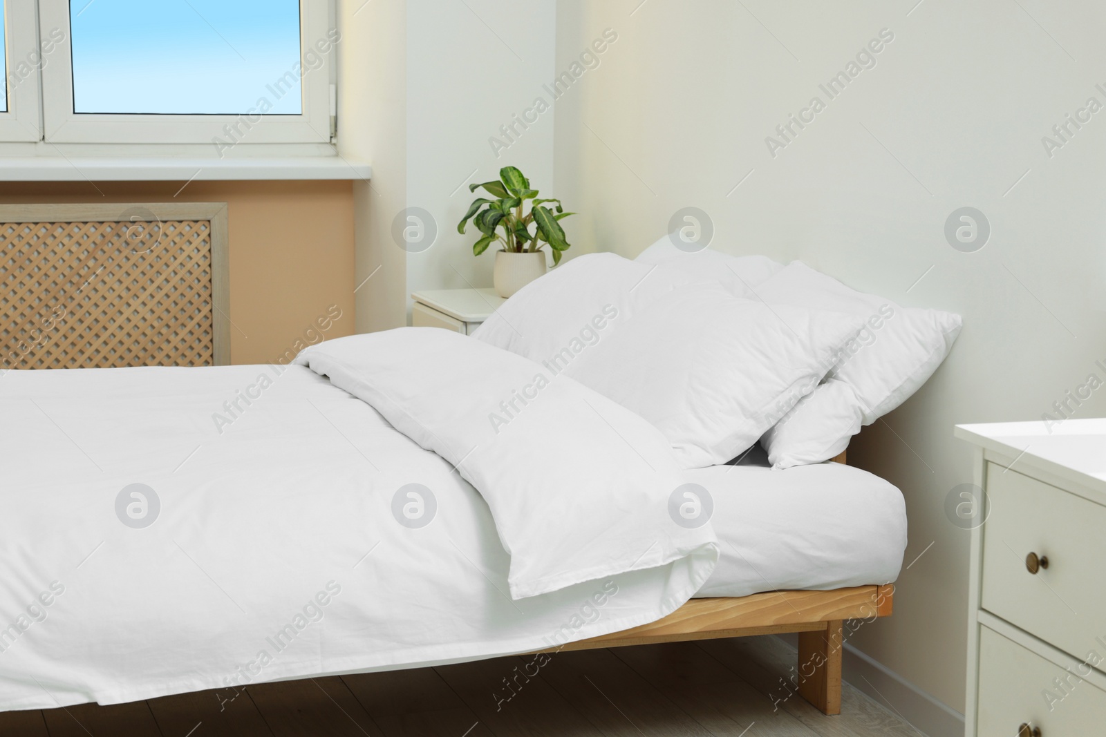 Photo of White soft pillows on cozy bed in room