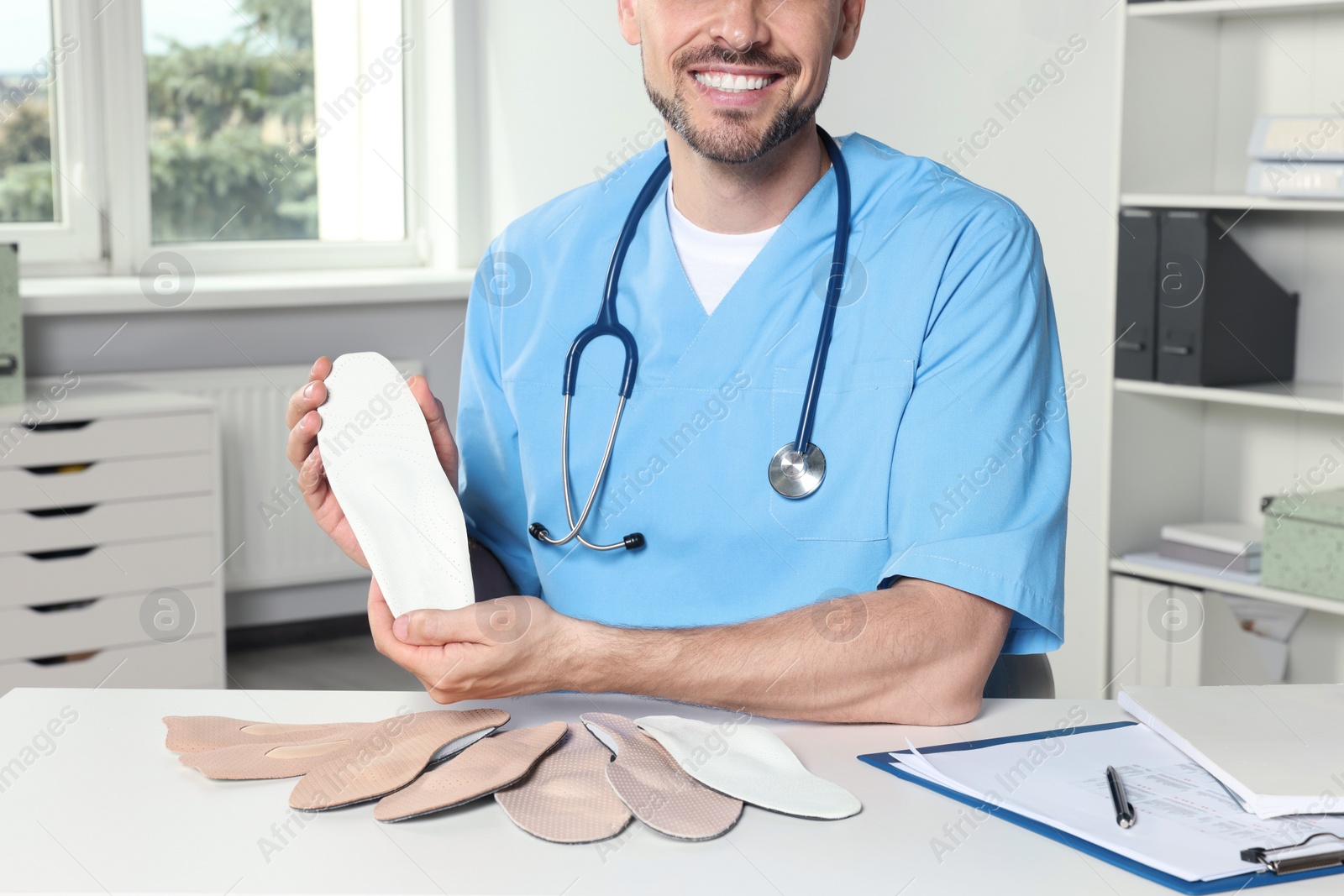 Photo of Male orthopedist showing insoles in hospital, closeup