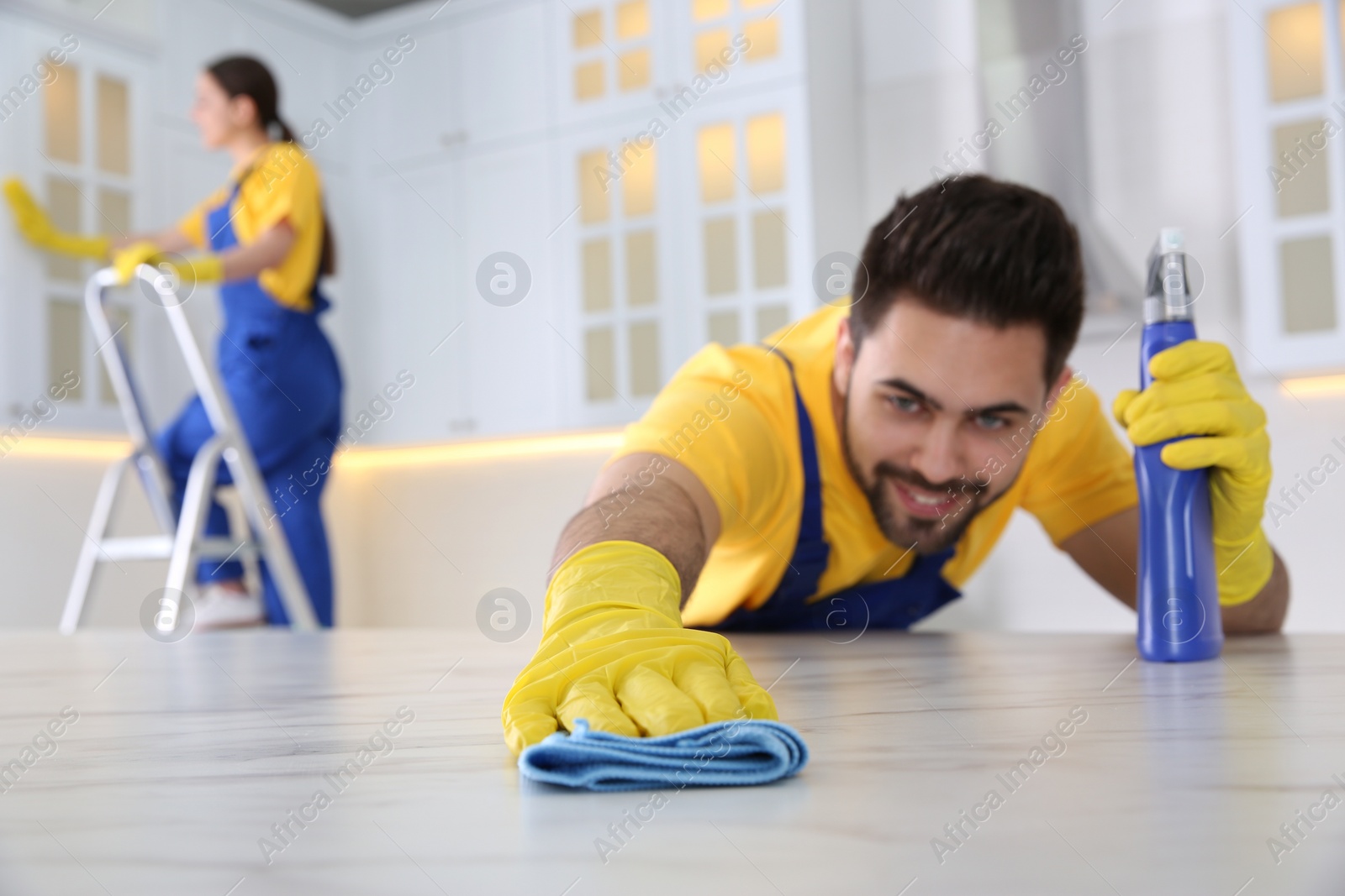 Photo of Professional young janitor cleaning table in kitchen