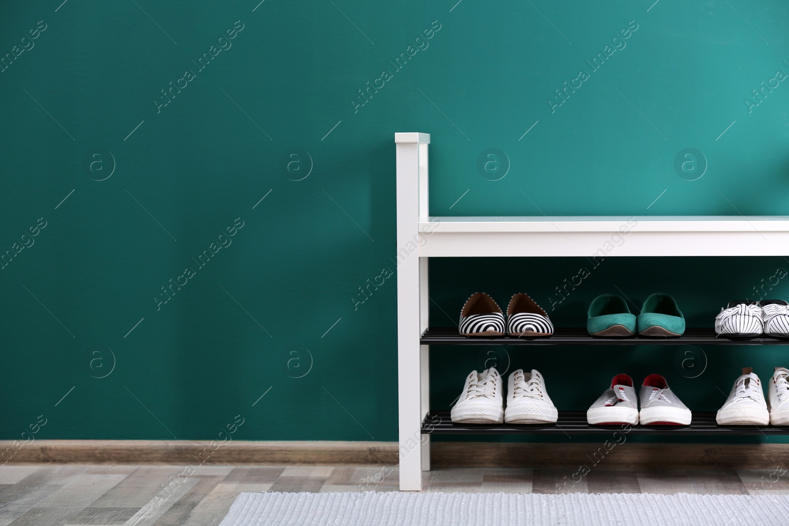 Photo of Shoe rack with different footwear near color wall, space for text. Stylish hallway interior