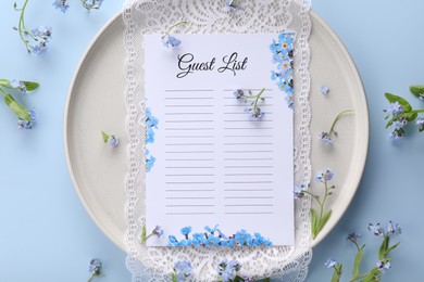 Plate with guest list, lace and flowers on light blue background, flat lay. Space for text