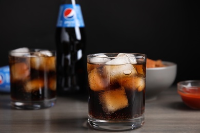 MYKOLAIV, UKRAINE - FEBRUARY 15, 2021: Glass of Pepsi with ice on wooden table