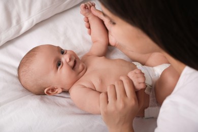 Young mother with her cute baby on bed, closeup