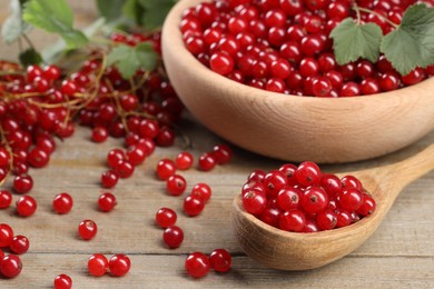 Photo of Ripe red currants and leaves on wooden table