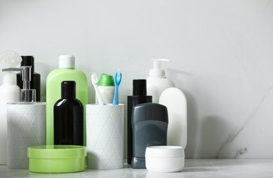 Photo of Stick deodorant and different toiletry on marble table near light wall, space for text