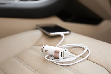 Adapter with connected charging cable and mobile phone in car, closeup