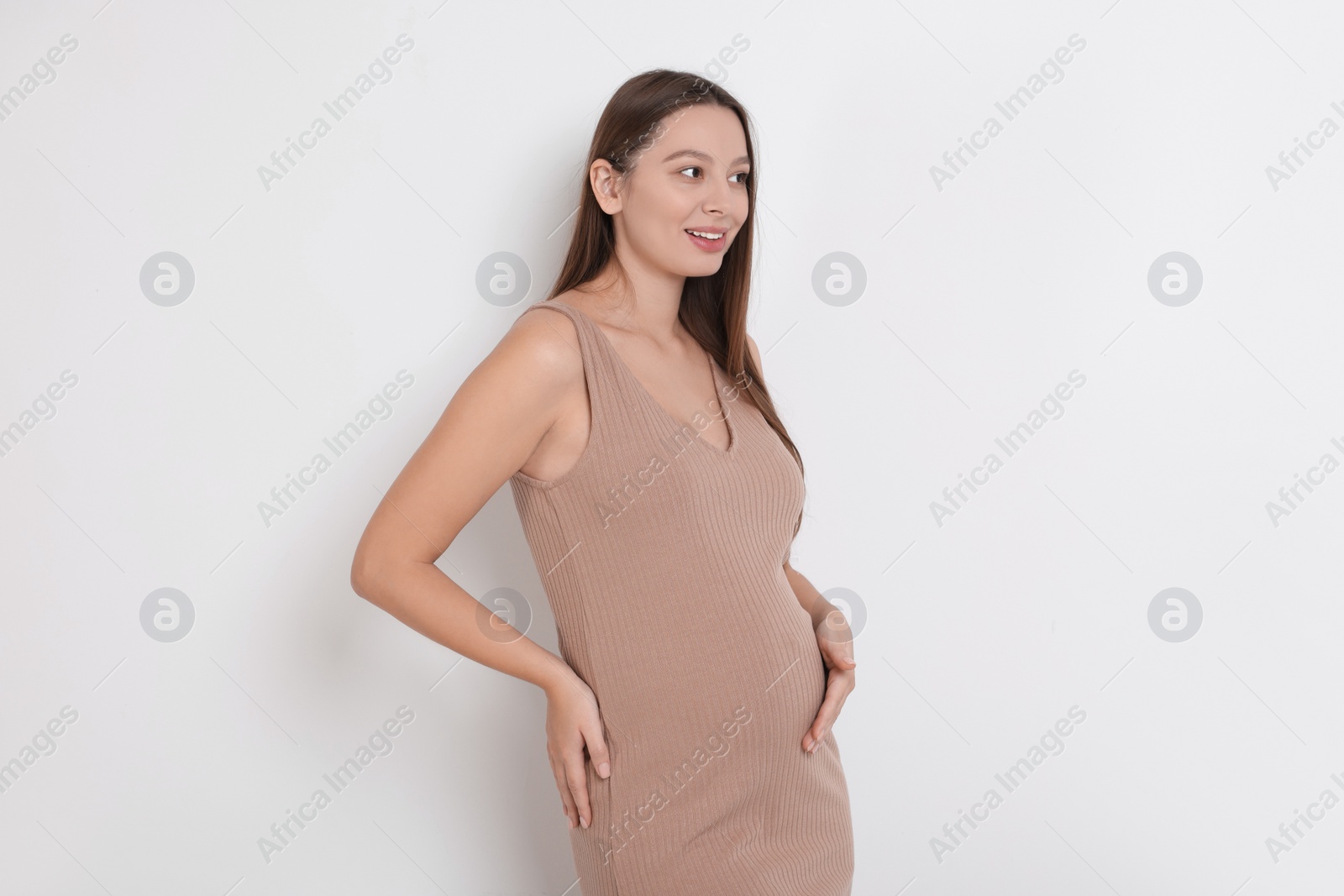 Photo of Beautiful pregnant woman in beige dress on white background