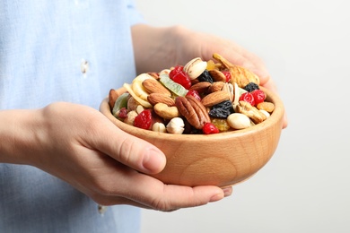 Young woman holding bowl with different dried fruits and nuts, closeup