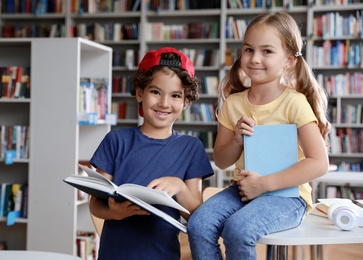 Little boy and girl reading book in library