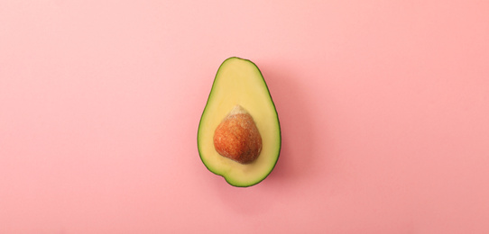 Half of delicious avocado on pink background, top view. Banner design