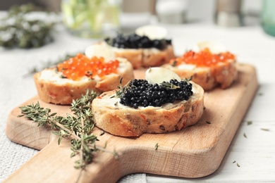 Photo of Sandwiches with black and red caviar on wooden board