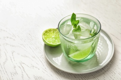 Refreshing beverage with mint and lime in glass on table