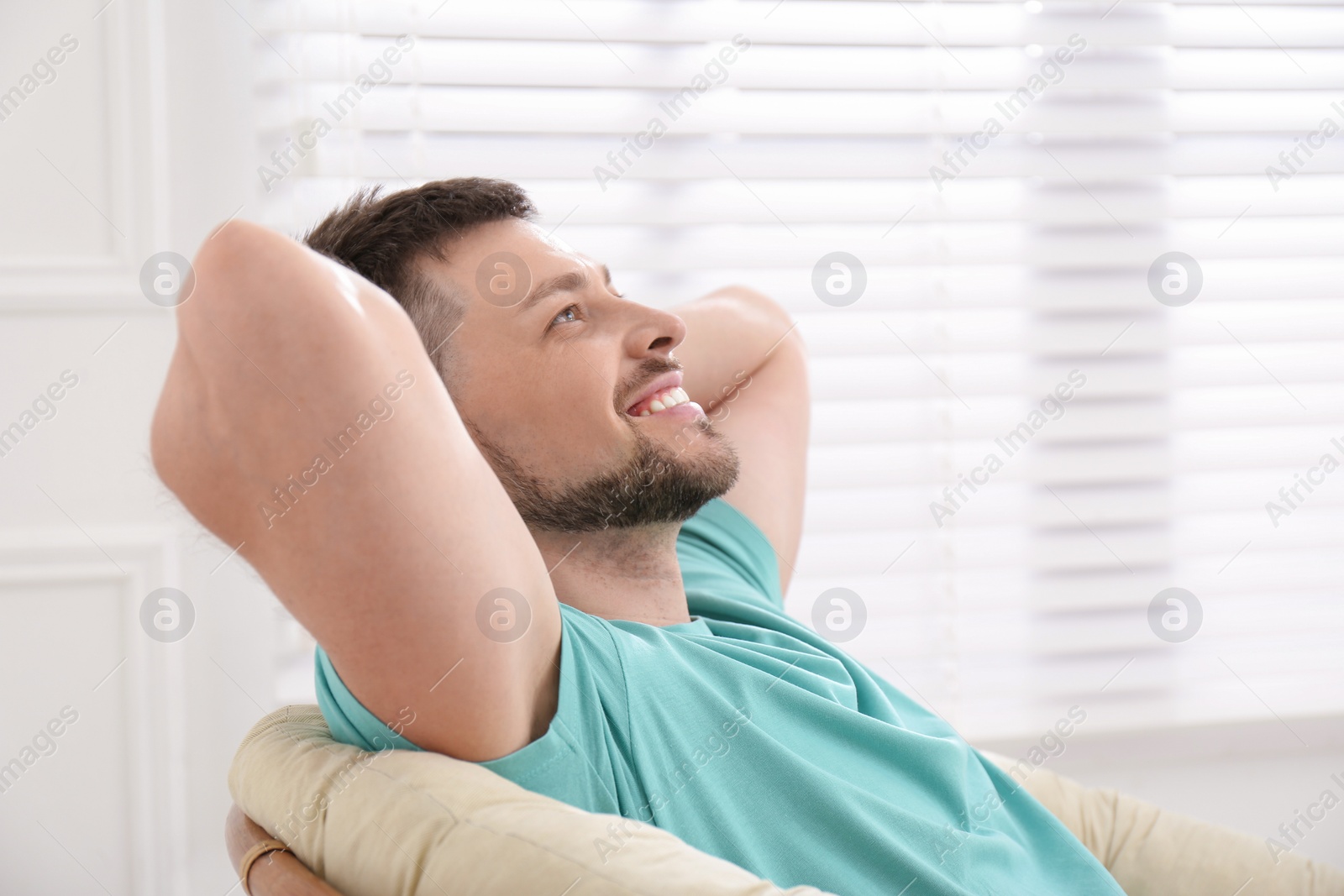 Photo of Handsome man relaxing in papasan chair indoors