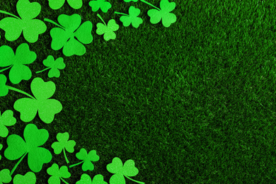 Flat lay composition with clover leaves on green grass, space for text. St. Patrick's Day celebration